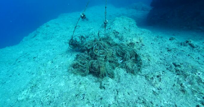scuba divers picking old nets and fishing cages underwater ghost hunting dangerous ocean scenery