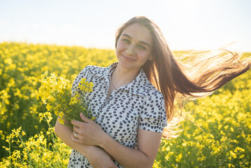 Beautiful girl in a rapeseed field, with her hair in the sun.