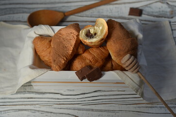 croissants with chocolate filling in a small wooden box with a cup of coffee on the table