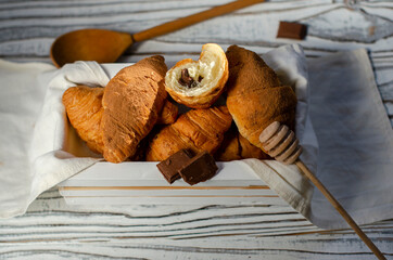 croissants with chocolate filling in a small wooden box with a cup of coffee on the table