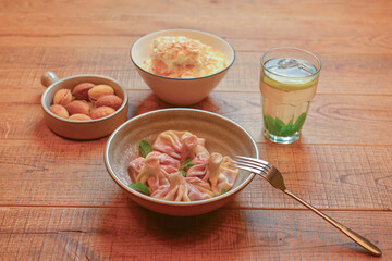 Sweet khinkali with cherry, Cookies called nuts with condensed milk and Cake Napoleon served in white plates.