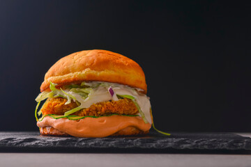 Juicy delicious craft burger with spices on a black background. Fast food, junk food concept.