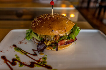 Hamburger in the white plate on a table. Rustic closeup.