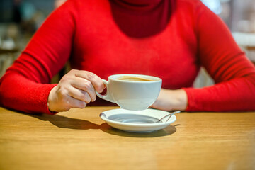 A girl drinks coffee at a table in a cafe
