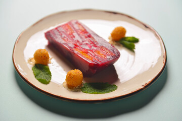 Red and pink layers of gelatin dessert served on a white plate over black wooden table.