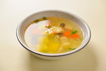 Delicious stew soup with meat and vegetables served in a white bowl over bright pastel yellow background. Healthy diet.