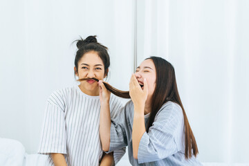 Two beautiful asian women are having fun and making fake mustaches from hair