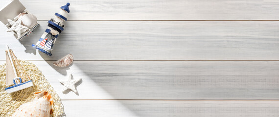Top view summer rustic blue lighthouse and seashell decorate on white wooden table with sunlight shade