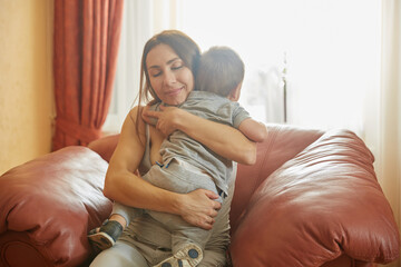 Fototapeta premium Loving mother hugging adorable baby with pleasure