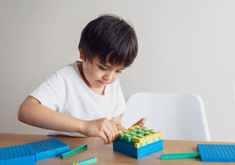 School kid using plastic block counting number,Child boy studying math by colour stack box,Montessori classroom material for children learning of mathematics at home,Home schooling, Distance education