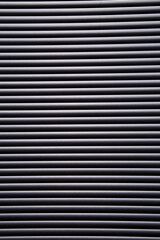 contrasty abstract close up filled frame background wallpaper shot of grey window blinds with rays of light shining through and leaving hard black shadows that create beautiful horizontal lines