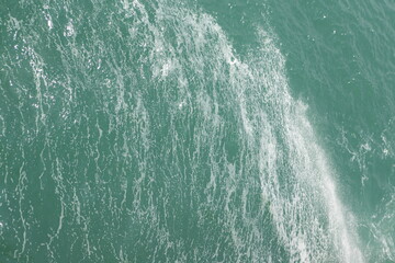 Fototapeta na wymiar filled frame full screen desktop wallpaper shot of troubled wavy blue turquoise sea water with white foam across