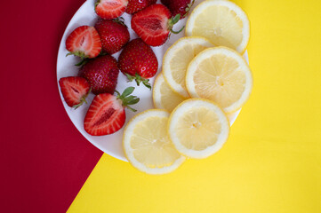 Fototapeta na wymiar Close up of lemon strawberry slices on red and yellow background, top view. Abstract, creative, creativity concept. Fresh juicy illustration for cafe restaurant Instagram, business.