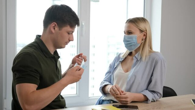 Isolated young couple due the pandemic situation. Man is putting on medicinal mask to prevent spread of viruses. Work from home and stay 