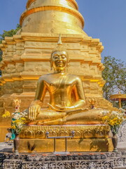 view of golden buddha statue lanna style art with golden pagoda and blue sky background, Wat Phra That Chomthong, Mueang Phayao, Phayao Province, northern of Thailand.
