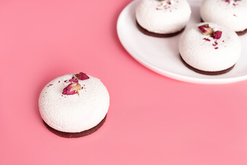 Mousse pastry dessert covered with white chocolate and decorated with rose buds on pastel pink background. Modern stylish cake. Copy space. Close-up.