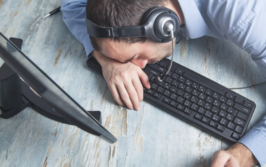 Tired call center operator sleeping in office desk.