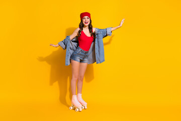 Fototapeta na wymiar Full body photo of positive cheerful sporty youngster girl ride roller skates hold hands imagine she fly wear red headwear tank-top denim isolated over bright color background