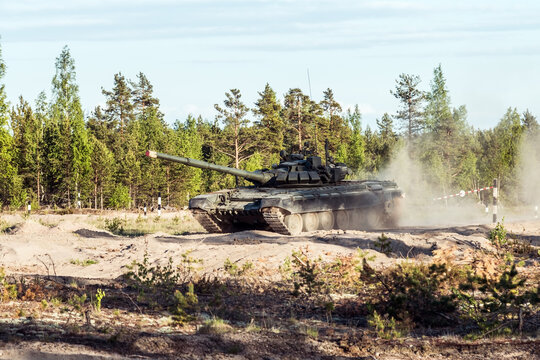 battle tank rides on a dusty road in the forest. Advanced tank of the Russian army t-90
