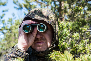 spy or scout looking through binoculars in the forest