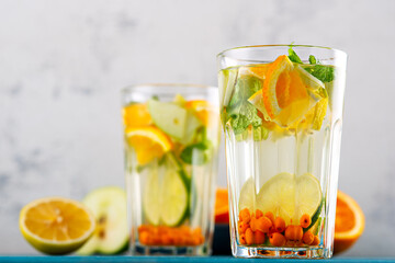 homemade lemonade with lemon, orange, sea buckthorn and mint in glasses on white background, summer drinks