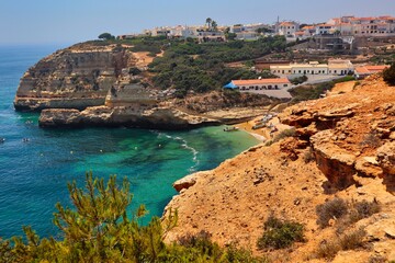 Fototapeta na wymiar Carvoeiro Beach from Hill with Turquoise Atlantic Ocean and Sandstone Cliff. Colorful White Architecture in the Carvoeiro Village.