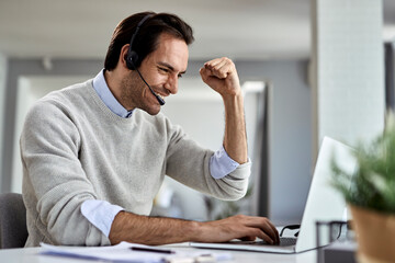 Happy businessman celebrating good news while working on a computer at home.