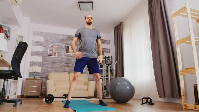 Male athlete training legs doing squat exercise at home. Sport at home and healthy lifestyle, activity, fitness and workout. Indoor training and home exercise