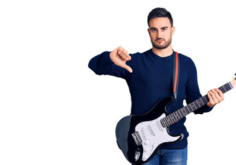 Young handsome man playing electric guitar with angry face, negative sign showing dislike with...