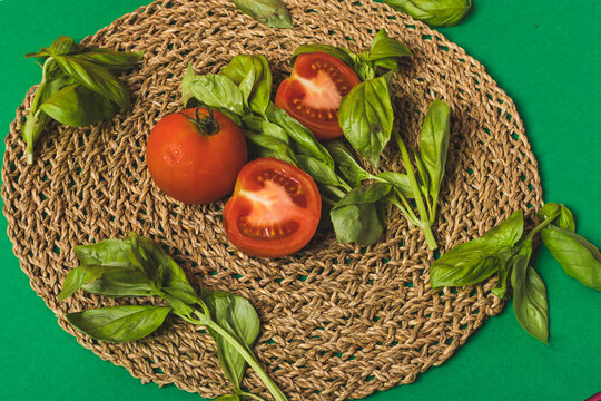 basil and tomatoes on a palm petate with a green background