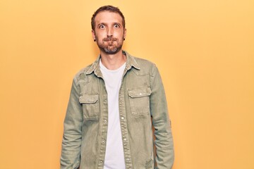 Young handsome man wearing casual clothes puffing cheeks with funny face. mouth inflated with air, crazy expression.