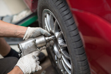 Fototapeta na wymiar Repair or changing tire car vehicle mechanic screwing car wheel at repair service station