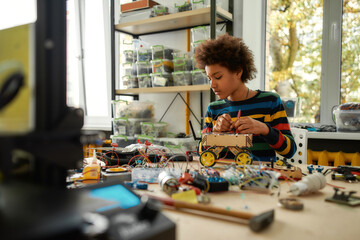 Passion in Every Work. Child programming, testing robot vehicle, working with wires and circuits at...