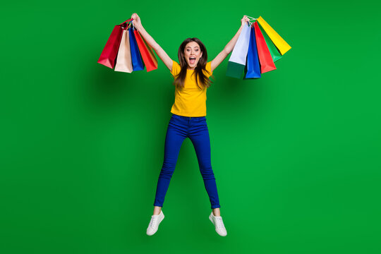 Full length body size view portrait of nice attractive pretty lovely glad crazy cheerful girl jumping carrying new clothes having fun isolated bright vivid shine vibrant green color background