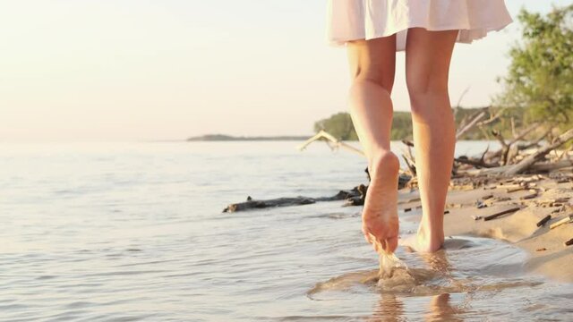 Woman legs on sandy beach. Girl walking on sand by the sea. Beach travel. Summer vacations concepts. 4k Cinematic.