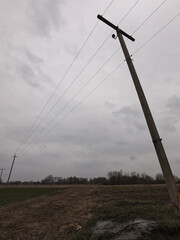 Electric pole in a field on a cloudy evening.