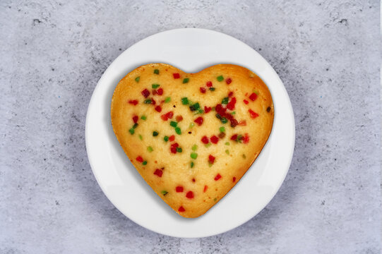 White Plate With Heart Shape Tutti Fruity Cake On A Table.