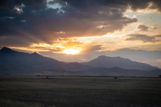 Sunset with the mountains of the zagros in the background and some horses running in the distance
