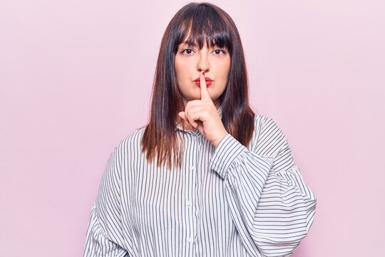 Young plus size woman wearing casual clothes asking to be quiet with finger on lips. silence and secret concept.