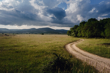 Beautiful country road before a thunderstorm at sunset.