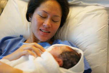 Asian Chinese woman holding her new born baby right after childbirth