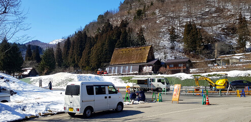 Japan - February 23, 2019: Small white van parked on street and people working and repairing or...