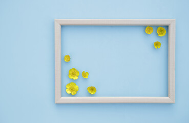 Spring floral background. Frame with fresh yellow flowers on a blue background. The concept of spring. Mother's Day, Women's Day. Flat lay, space for text. View from above.