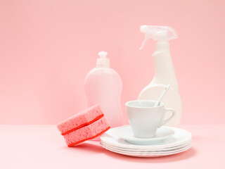 Bottles of dishwashing liquid and utensil on a pink background.