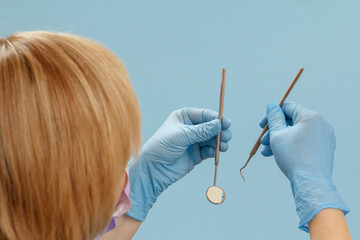 Dentist's hands with a probe and a mouth mirror.