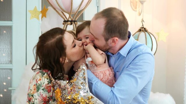 Young parents giving their daughter a kiss