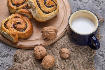 Obraz na płótnie Canvas Basket of homemade buns with jam, served on old wooden table with walnuts and cup of milk