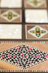 Vertical close-up detail of delicate handcrafted fine wood trinket box, luxury marquetry and mother of pearl inlaid case with colorful geometric pattern, used for jewelry or valuables