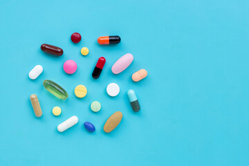 Colorful medicine pills, tablets and capsules on blue background.