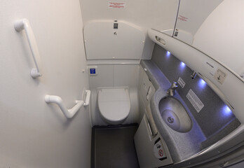 Bathroom of a passenger aircraft Boeing 737. Toilet bowl, sink, knob to drain water, seatcovers,...